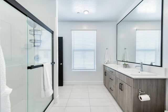 bathroom featuring tile patterned flooring, a sink, baseboards, a shower stall, and double vanity