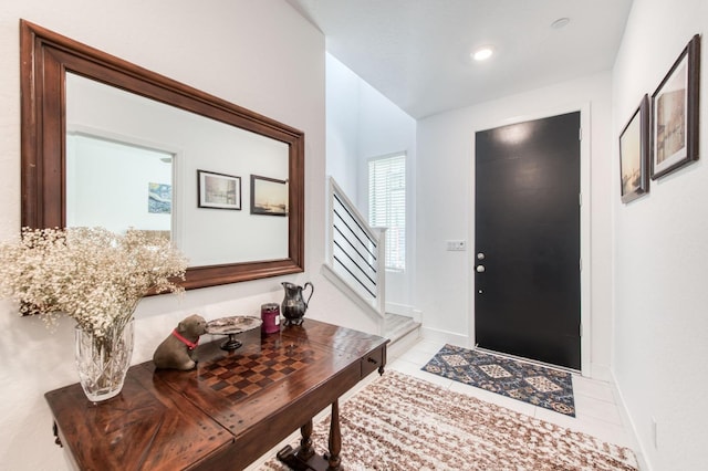 entryway with light tile patterned floors, stairway, and baseboards