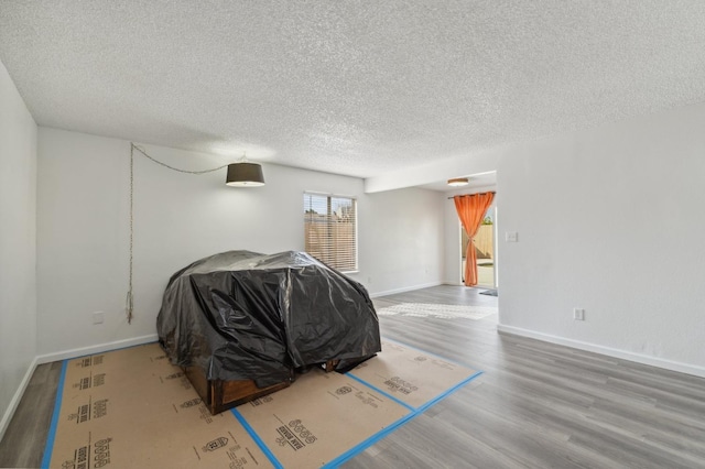 bedroom featuring a textured ceiling, baseboards, and wood finished floors