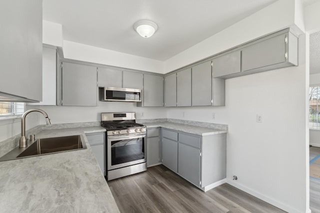 kitchen with appliances with stainless steel finishes, gray cabinets, light countertops, and a sink