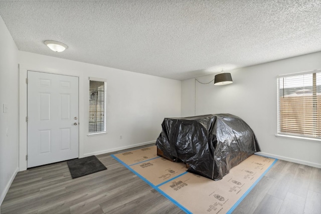 living room featuring a textured ceiling, baseboards, and wood finished floors