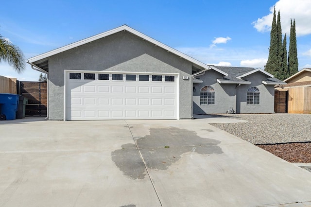 ranch-style home featuring an attached garage, fence, concrete driveway, and stucco siding