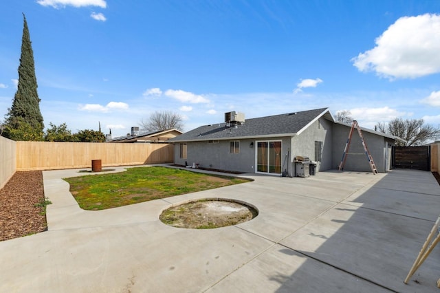 back of house featuring a lawn, a fenced backyard, and stucco siding