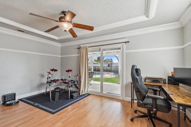 office space with light wood-style flooring, visible vents, a textured ceiling, and ornamental molding