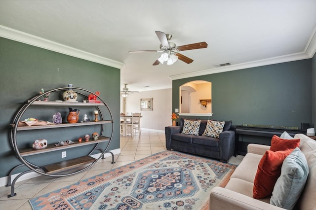 living area with crown molding, light tile patterned floors, visible vents, ceiling fan, and baseboards