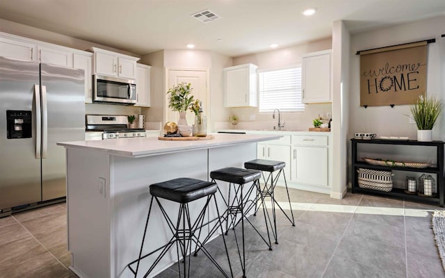 kitchen featuring visible vents, white cabinets, appliances with stainless steel finishes, a center island, and light countertops