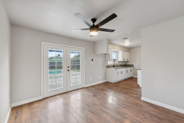 interior space with dark wood-style flooring, a sink, white cabinetry, baseboards, and french doors