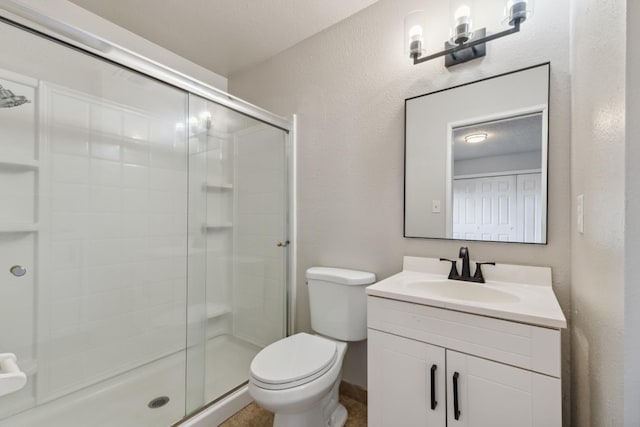 bathroom featuring a textured wall, a stall shower, vanity, and toilet