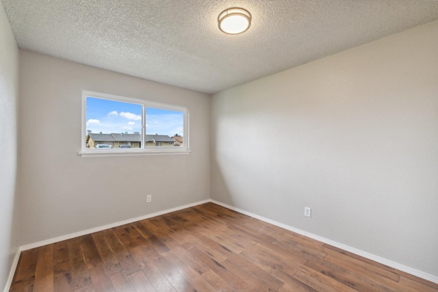 empty room featuring dark wood-style floors, baseboards, and a textured ceiling