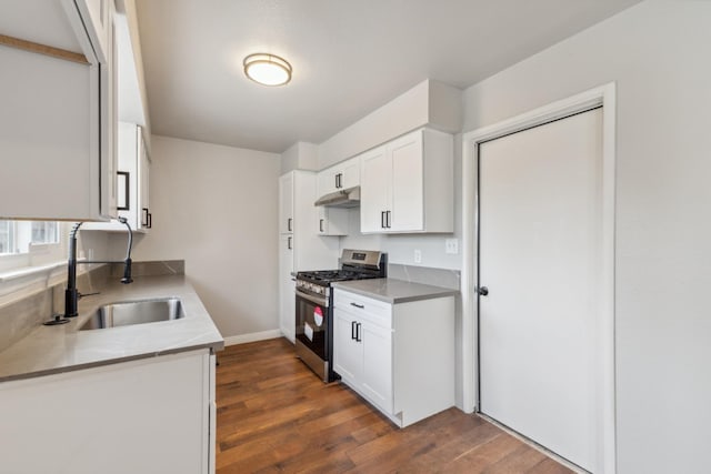 kitchen with dark wood-style floors, stainless steel range with gas stovetop, a sink, white cabinetry, and under cabinet range hood