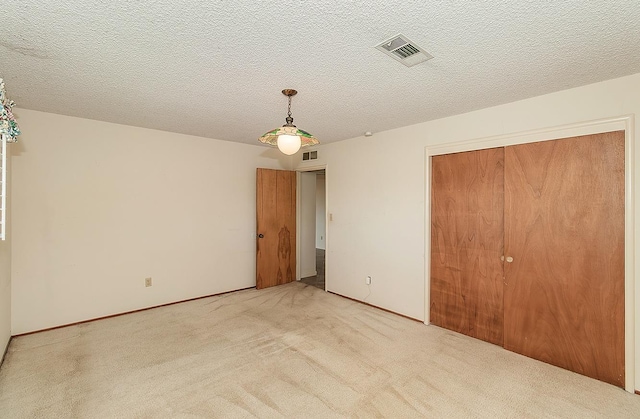 unfurnished bedroom featuring carpet, visible vents, and a textured ceiling