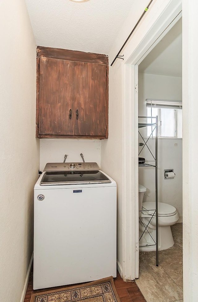 clothes washing area featuring cabinet space, washer / dryer, and baseboards