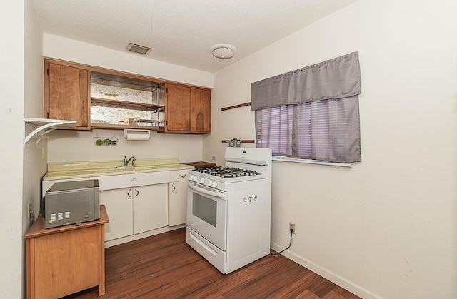 kitchen with white range with gas stovetop, light countertops, dark wood finished floors, and open shelves