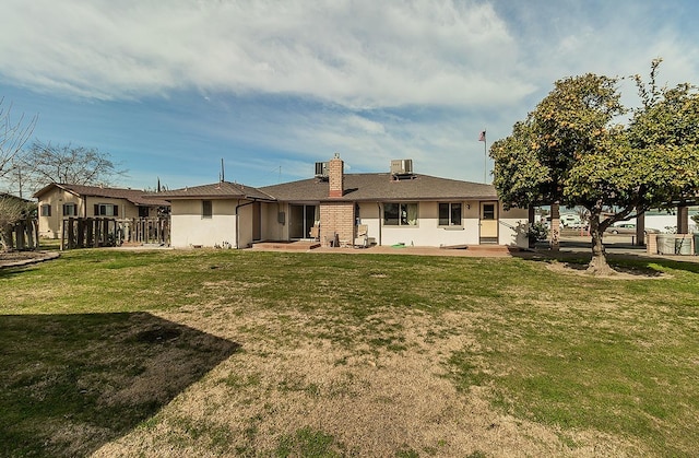 rear view of property featuring fence, a yard, central AC unit, and a patio