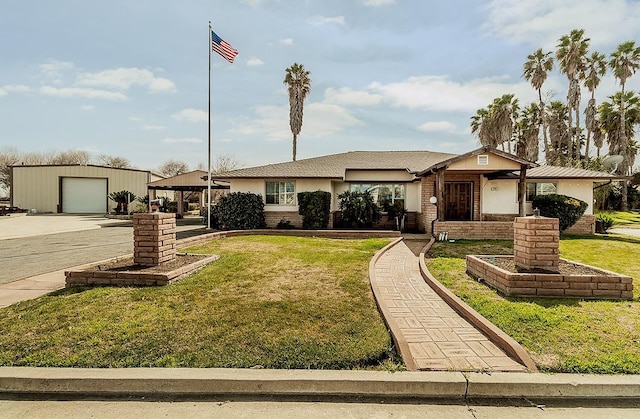 ranch-style home featuring a garage, stucco siding, an outdoor structure, a front yard, and brick siding