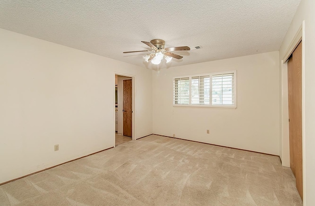 unfurnished bedroom featuring a closet, a textured ceiling, and light colored carpet