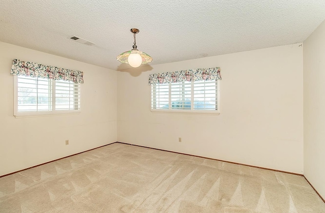 carpeted spare room featuring a textured ceiling and visible vents