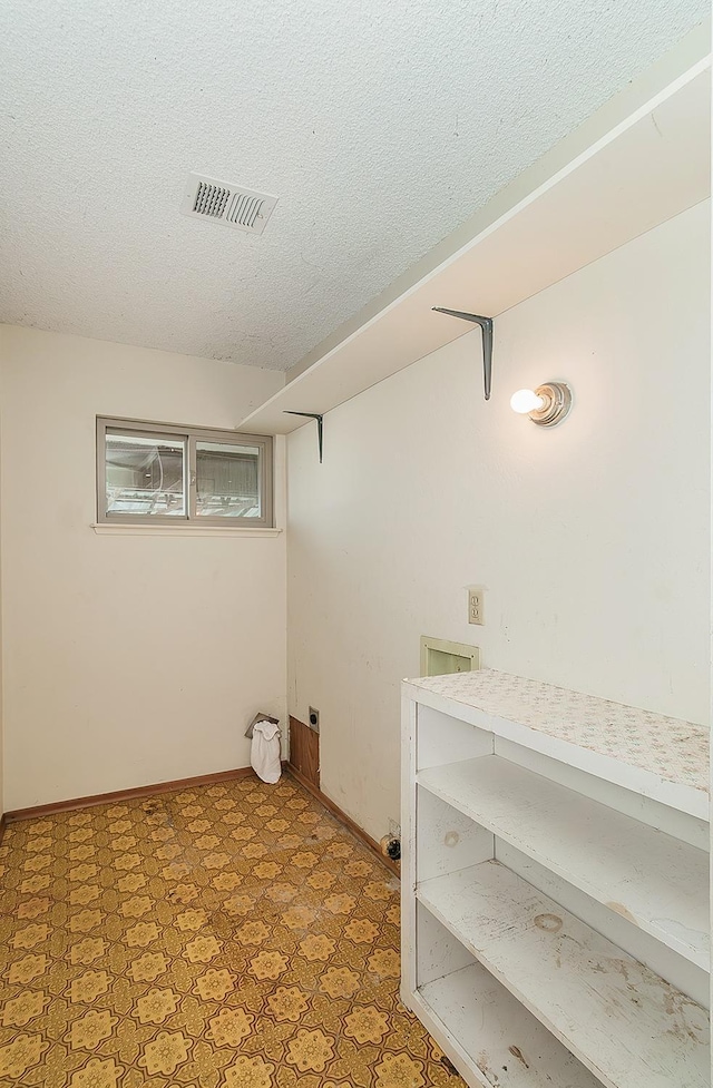 laundry area featuring visible vents, a textured ceiling, baseboards, and tile patterned floors