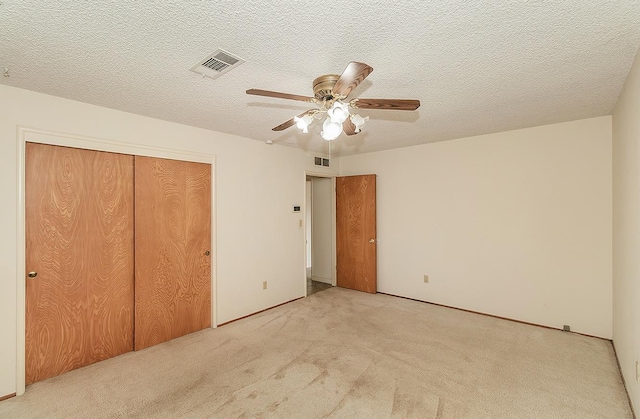 unfurnished bedroom featuring light carpet, a closet, visible vents, and a textured ceiling