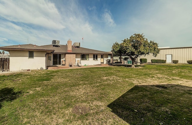 back of house with central AC, a lawn, a chimney, and fence