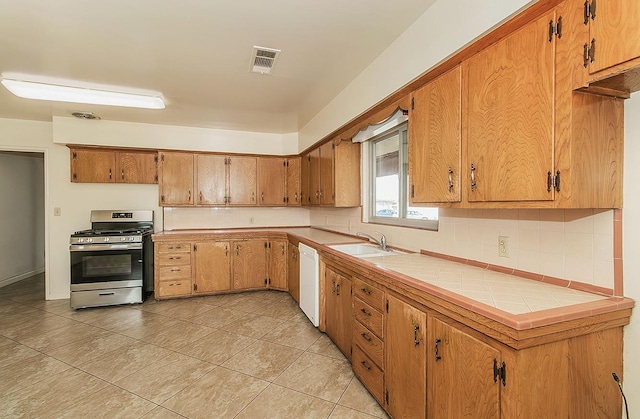 kitchen featuring stainless steel gas range oven, visible vents, brown cabinets, and dishwasher