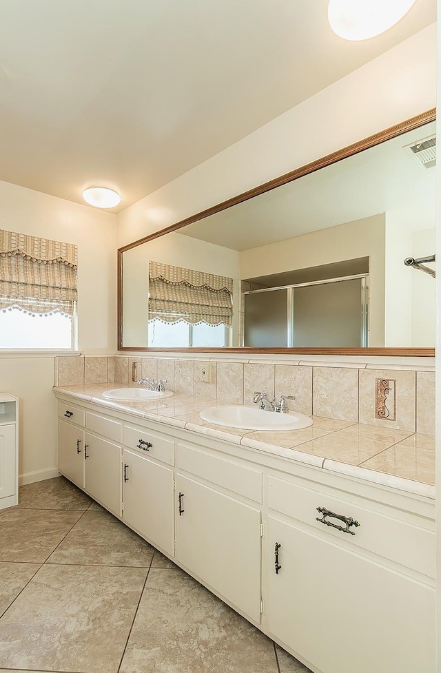 bathroom featuring double vanity, tasteful backsplash, visible vents, and a sink