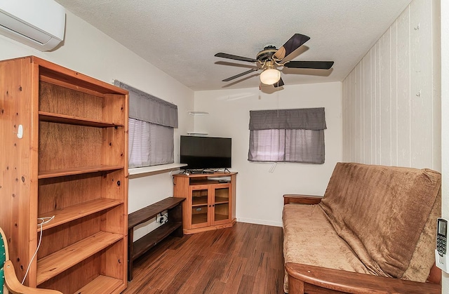 living area with dark wood-style floors, ceiling fan, a textured ceiling, and a wall mounted AC