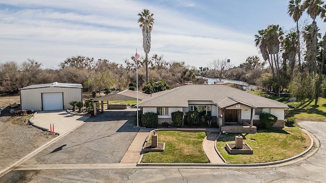 view of front of property featuring driveway, a front yard, a carport, and an outbuilding