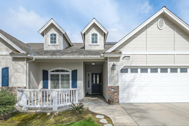 view of front facade with concrete driveway, stone siding, roof with shingles, an attached garage, and covered porch