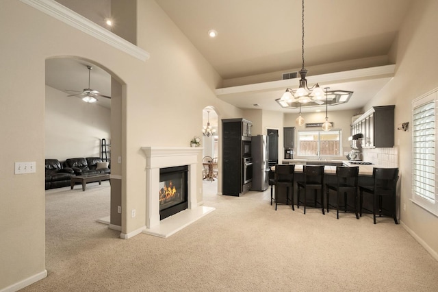 kitchen featuring arched walkways, a breakfast bar area, light colored carpet, light countertops, and open floor plan