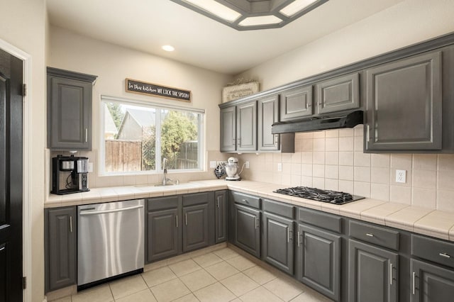 kitchen featuring dishwasher, gas stovetop, tile counters, and under cabinet range hood