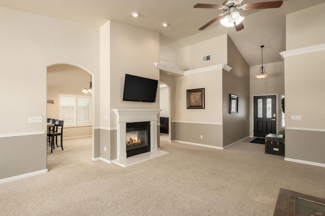 living area featuring light carpet, visible vents, arched walkways, high vaulted ceiling, and a multi sided fireplace