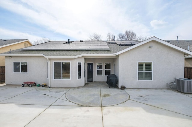 rear view of property featuring a patio, cooling unit, a shingled roof, roof mounted solar panels, and stucco siding