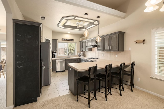 kitchen featuring light tile patterned floors, a breakfast bar area, stainless steel appliances, a peninsula, and tasteful backsplash