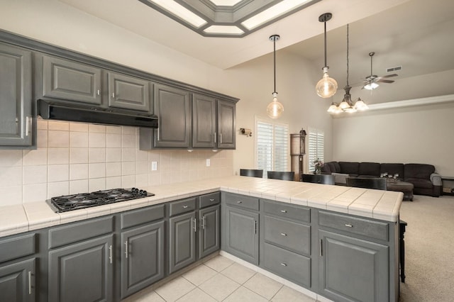 kitchen featuring gray cabinetry, under cabinet range hood, a peninsula, gas stovetop, and open floor plan