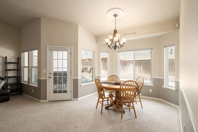 dining space featuring a chandelier, carpet, lofted ceiling, and baseboards