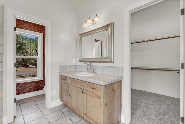 bathroom with tile patterned flooring, toilet, vanity, baseboards, and a spacious closet