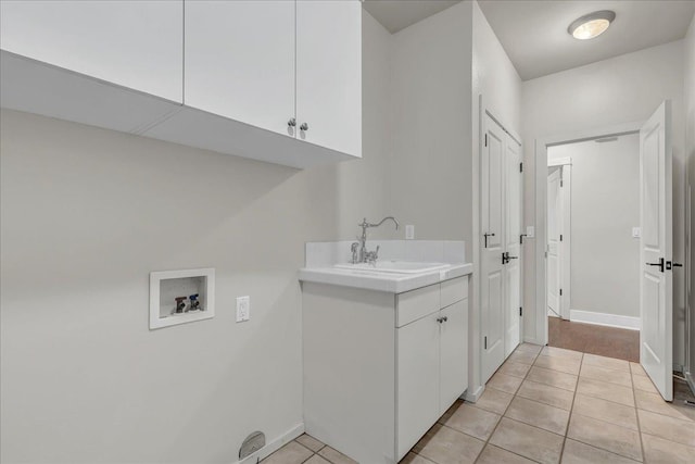 laundry area with washer hookup, cabinet space, light tile patterned flooring, a sink, and baseboards