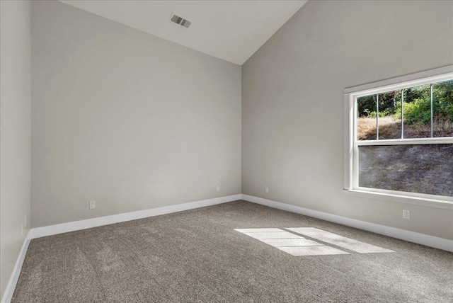 carpeted empty room with lofted ceiling, baseboards, and visible vents