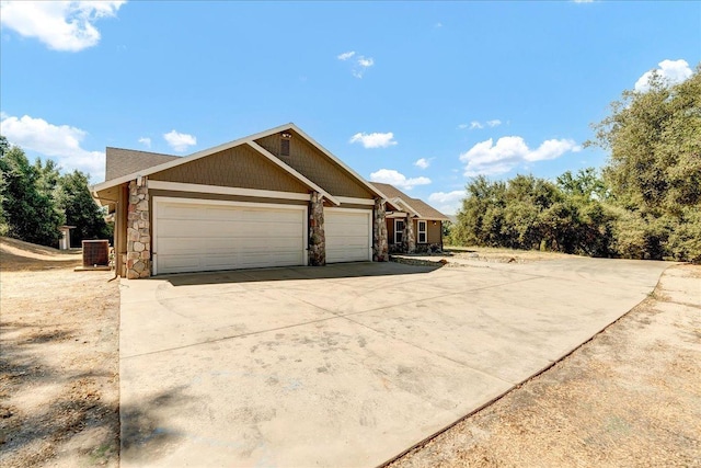 view of front of home with a garage, stone siding, concrete driveway, and central air condition unit