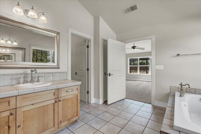 full bath featuring vanity, baseboards, vaulted ceiling, visible vents, and tile patterned floors