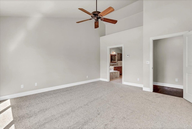 unfurnished bedroom featuring ensuite bathroom, high vaulted ceiling, ceiling fan, baseboards, and carpet