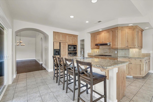 kitchen featuring visible vents, appliances with stainless steel finishes, a sink, an island with sink, and under cabinet range hood