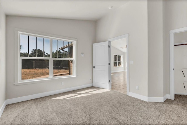 unfurnished bedroom with light carpet, baseboards, and lofted ceiling