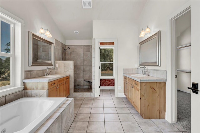 full bathroom featuring two vanities, tile patterned flooring, tiled shower, and a sink