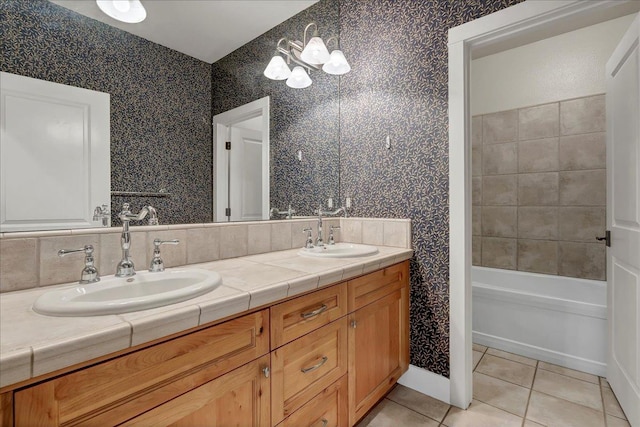 bathroom featuring tile patterned flooring, double vanity, a sink, and wallpapered walls