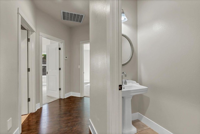 bathroom featuring a sink, wood finished floors, visible vents, and baseboards