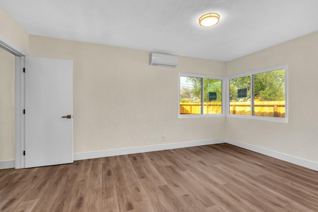 506 W Terrace Ave, Fresno, CA 93705 - unfurnished room with an AC wall unit, baseboards, wood finished floors, and a textured wall