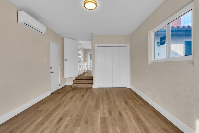 506 W Terrace Ave, Fresno, CA 93705 - empty room with an AC wall unit, light wood finished floors, baseboards, and stairway