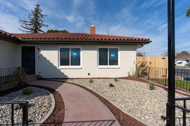 506 W Terrace Ave, Fresno, CA 93705 - back of house featuring a chimney, fence, brick siding, and a tiled roof